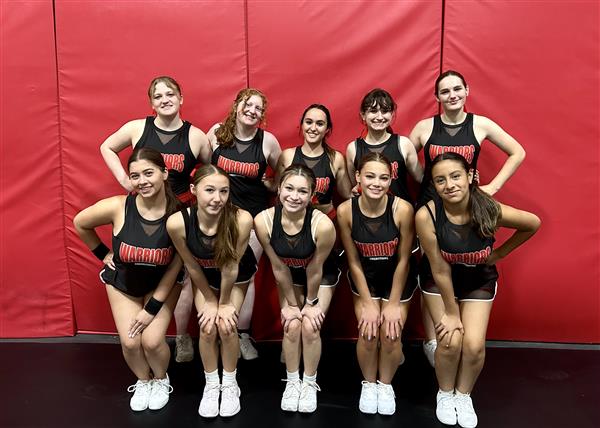 Cheerleaders posing with a red wall